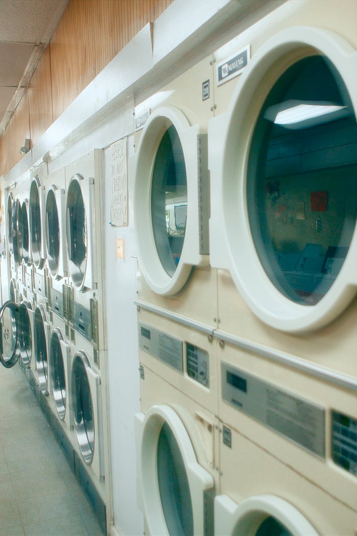 Interior view of a clean and organized laundromat with multiple washing machines lined up.